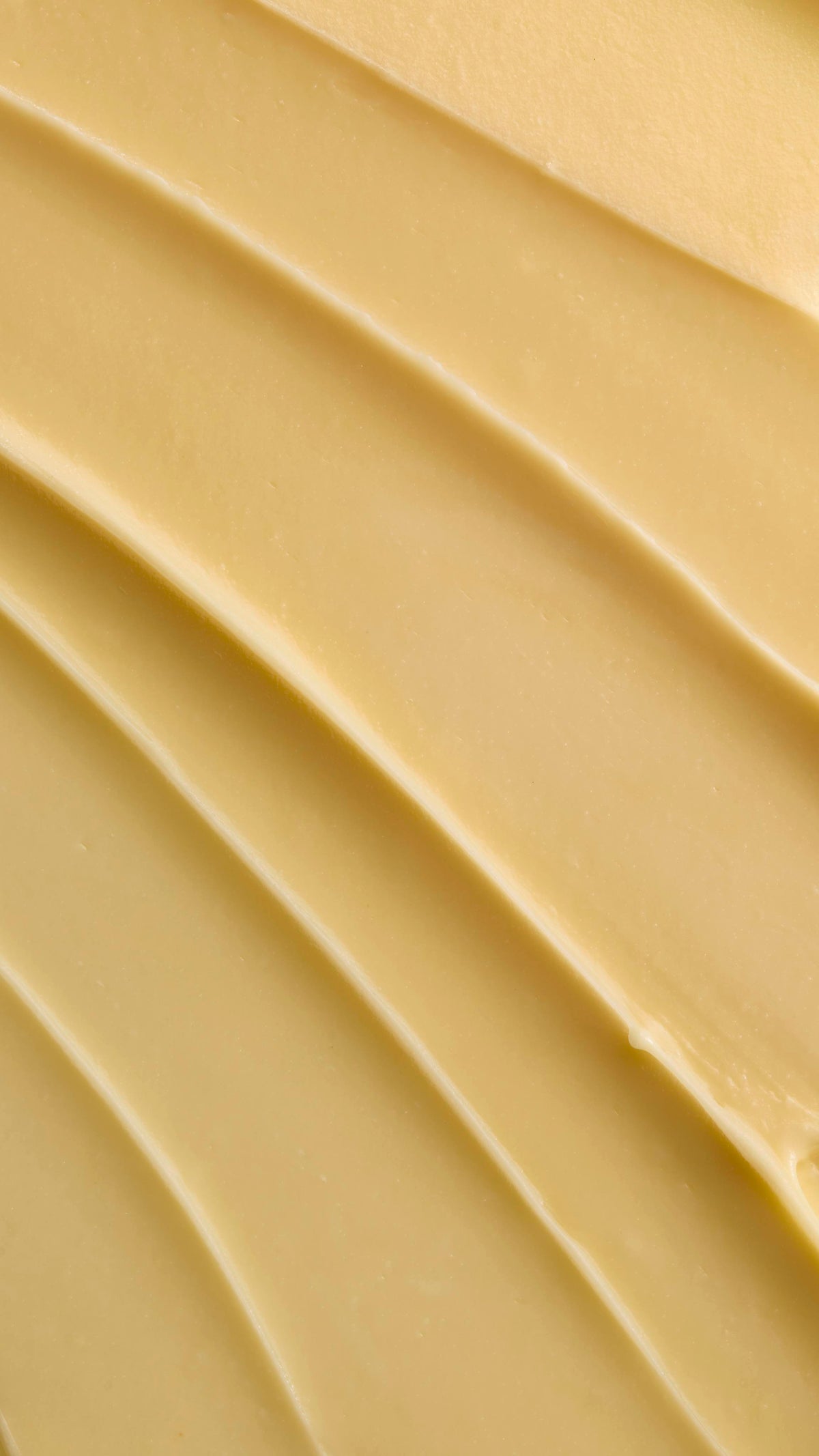 A close-up texture shot of pale yellow Ultrabland cleanser spread out in thick, smooth ridges, highlighting its rich and creamy consistency.